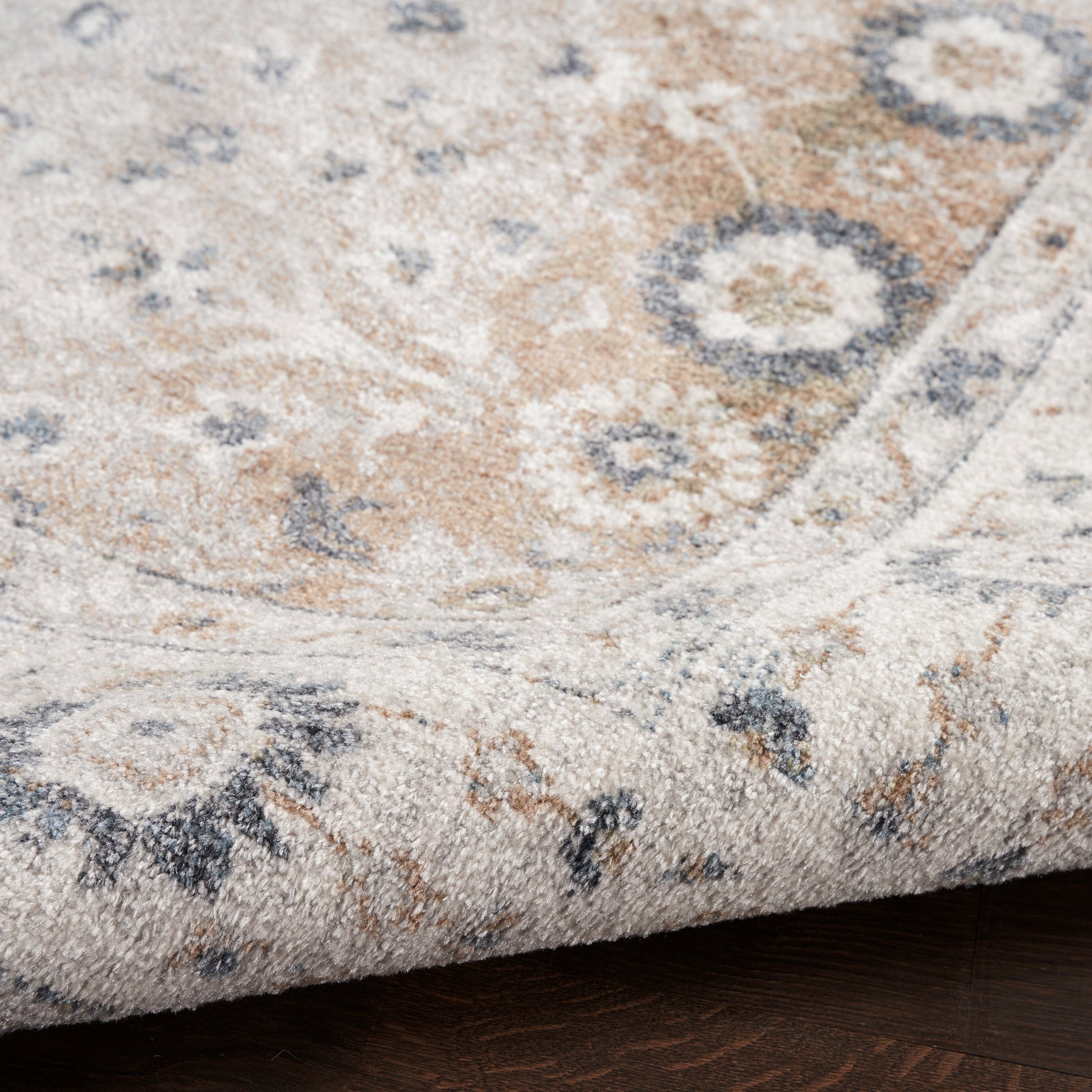 Beige distressed oriental-style area rug with blue-gray floral medallions; rolled edge and soft textured pile.