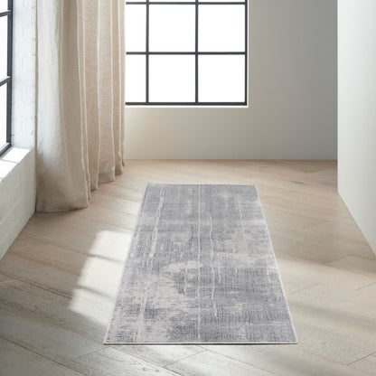 Rectangular gray-blue distressed rug on light wood floor beside beige curtains and a large grid window.