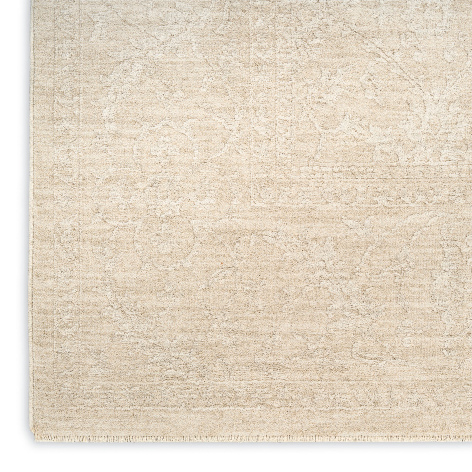 Beige textured area rug with a subtle floral pattern and cream tones, fringed edge.