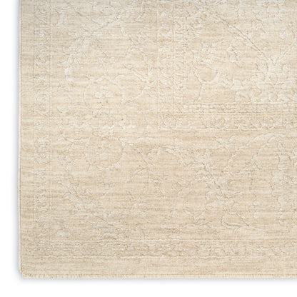 Beige textured area rug with a subtle floral pattern and cream tones, fringed edge.