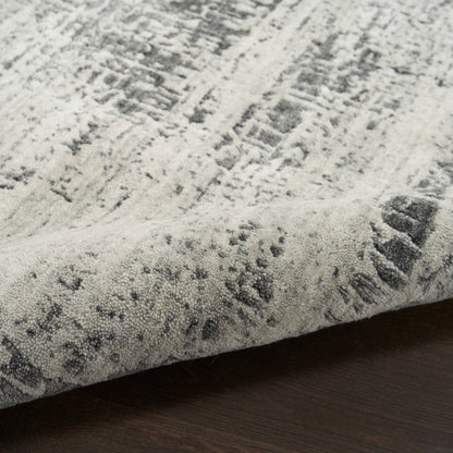 Light grey and ivory abstract textured area rug with a modern geometric pattern and tufted pile on a dark wood floor.