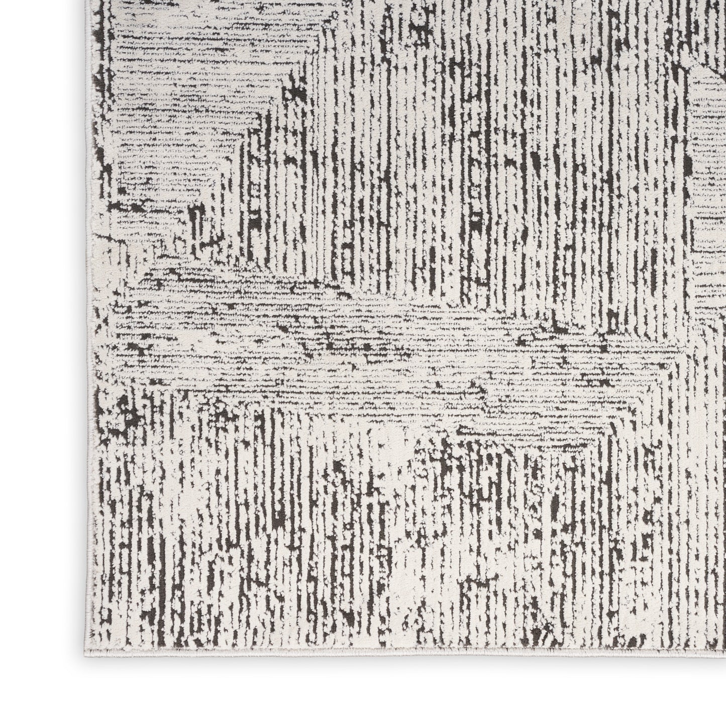 Monochrome woven rug with bold geometric linear pattern in black on white, corner view.