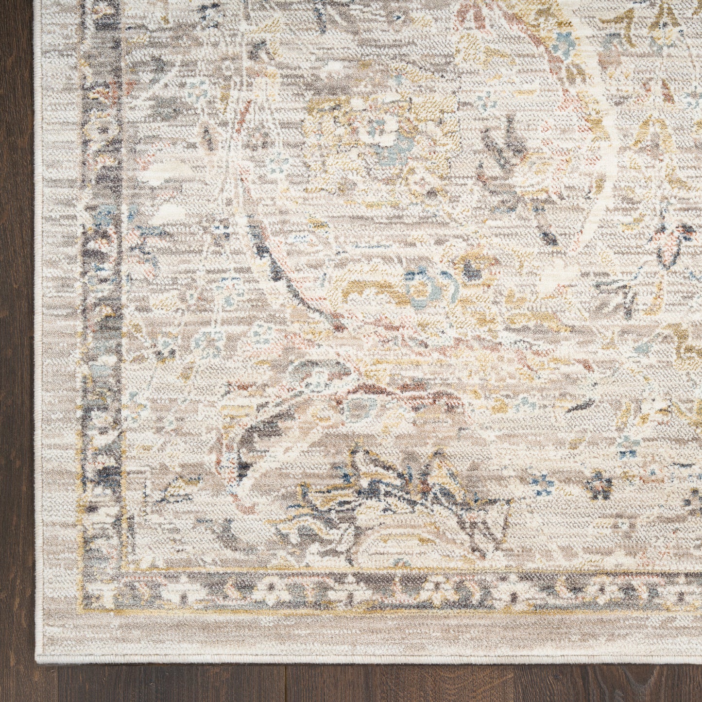 Beige distressed oriental rug with faded floral medallion, ornate border, blue and gold accents on a wood floor.