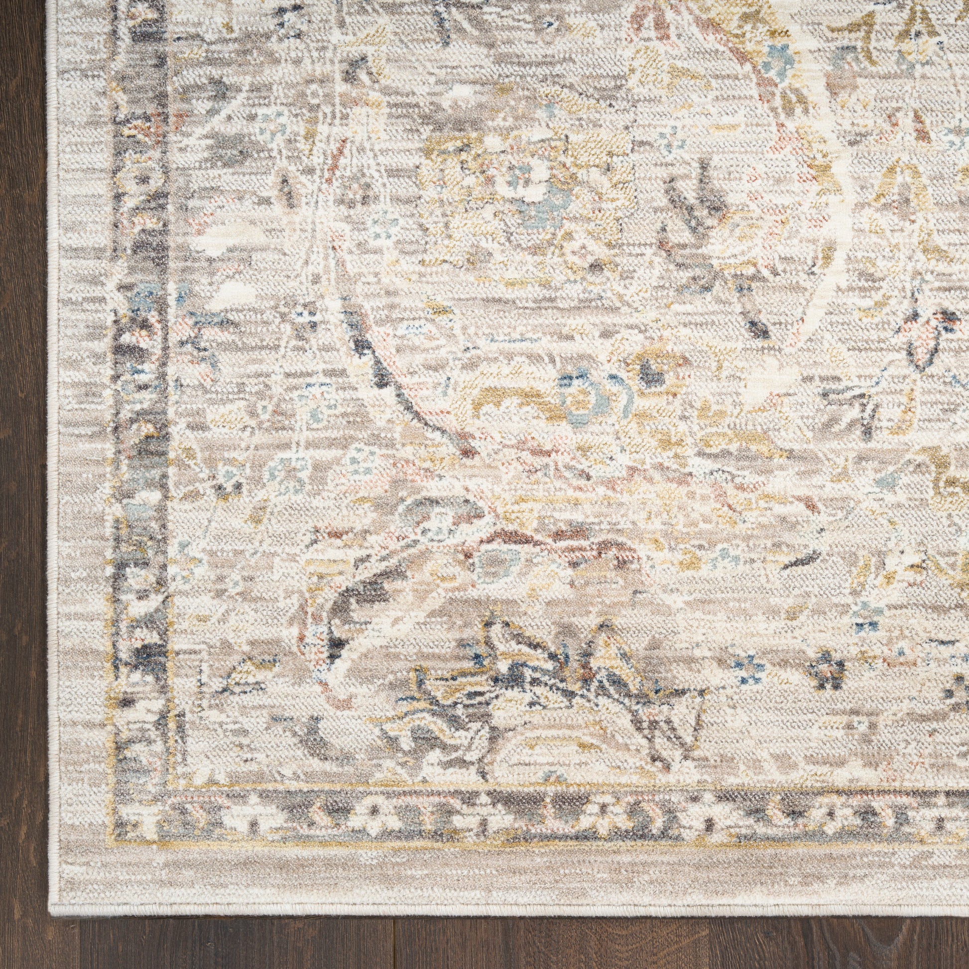 Beige distressed oriental rug with faded floral medallion, ornate border, blue and gold accents on a wood floor.