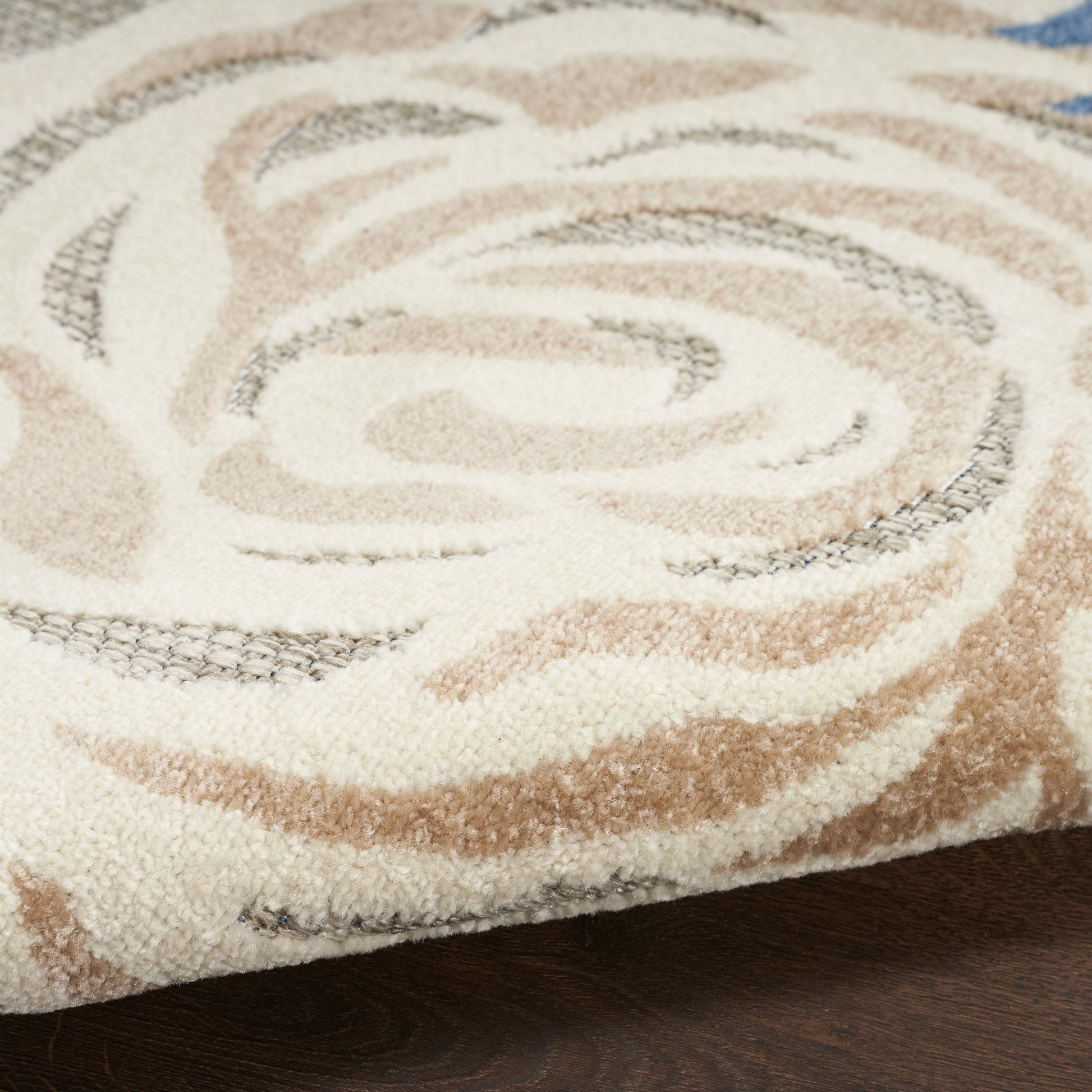 Beige and tan swirl-pattern shag rug with plush pile, ideal for living room decor on dark hardwood floor.