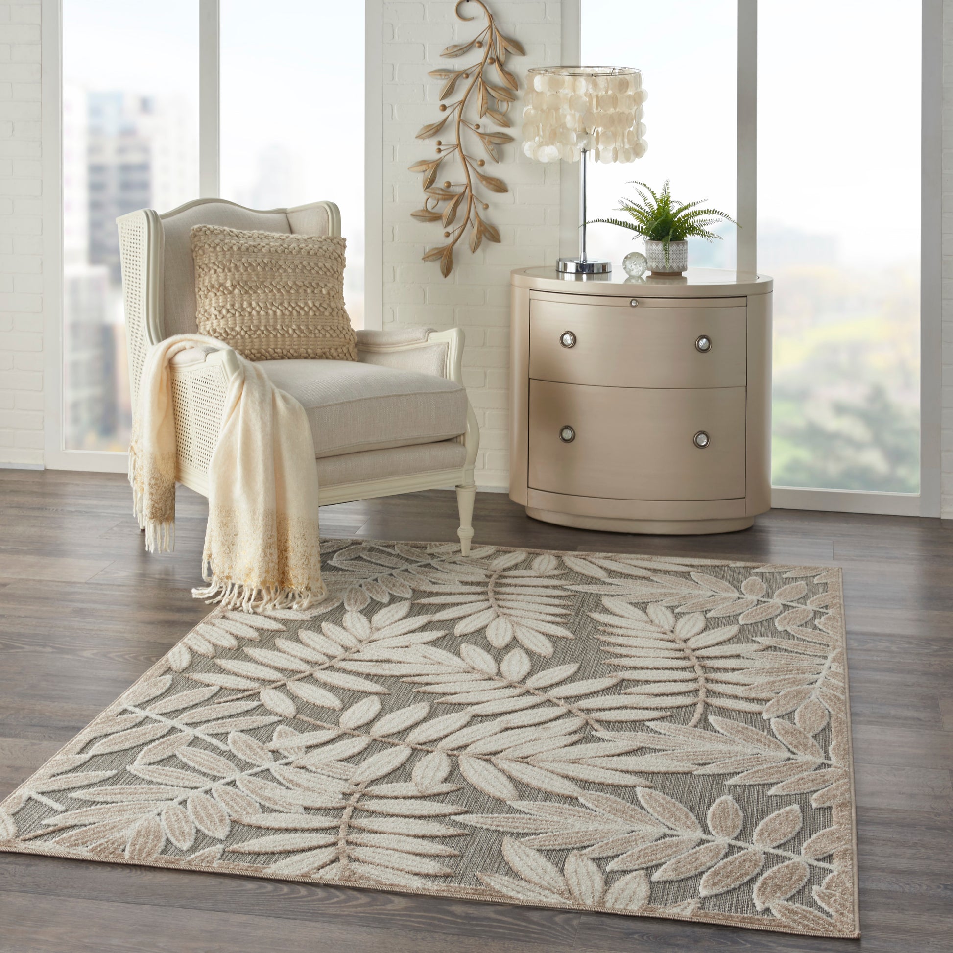 Beige tropical rug with a botanical leaf pattern in a bright, windowed living space.