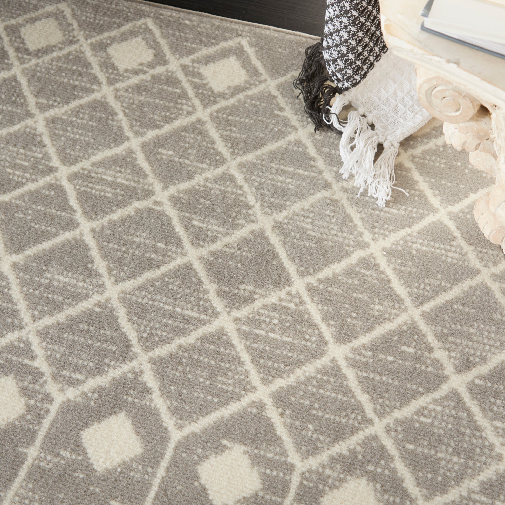 Gray woven area rug with white diamond lattice pattern and fringe edge.