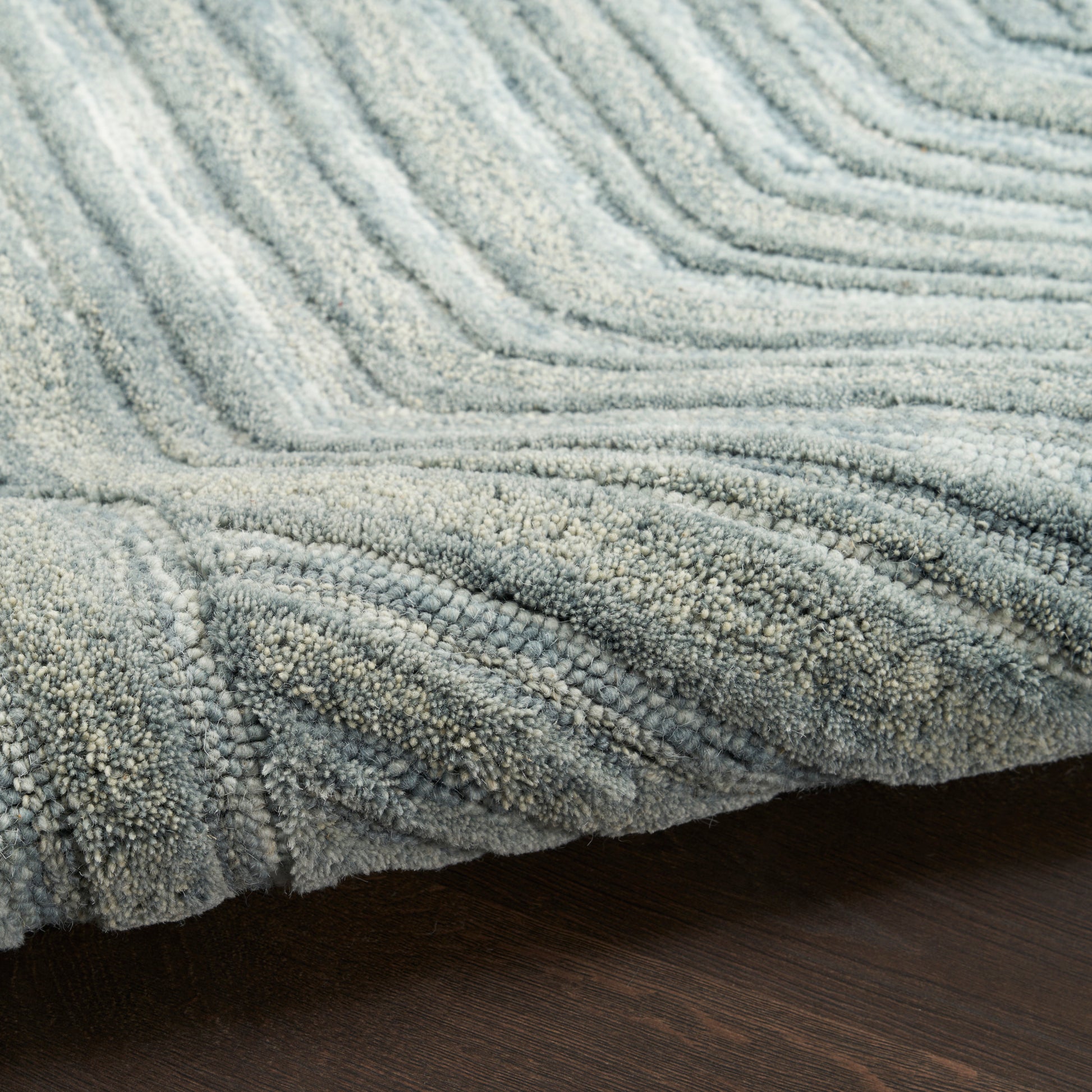 Light blue-gray shag rug with thick looped pile and plush textured fibers on dark wooden floor.