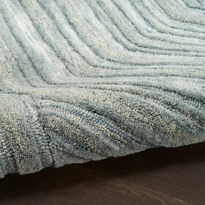 Light blue-gray shag rug with thick looped pile and plush textured fibers on dark wooden floor.