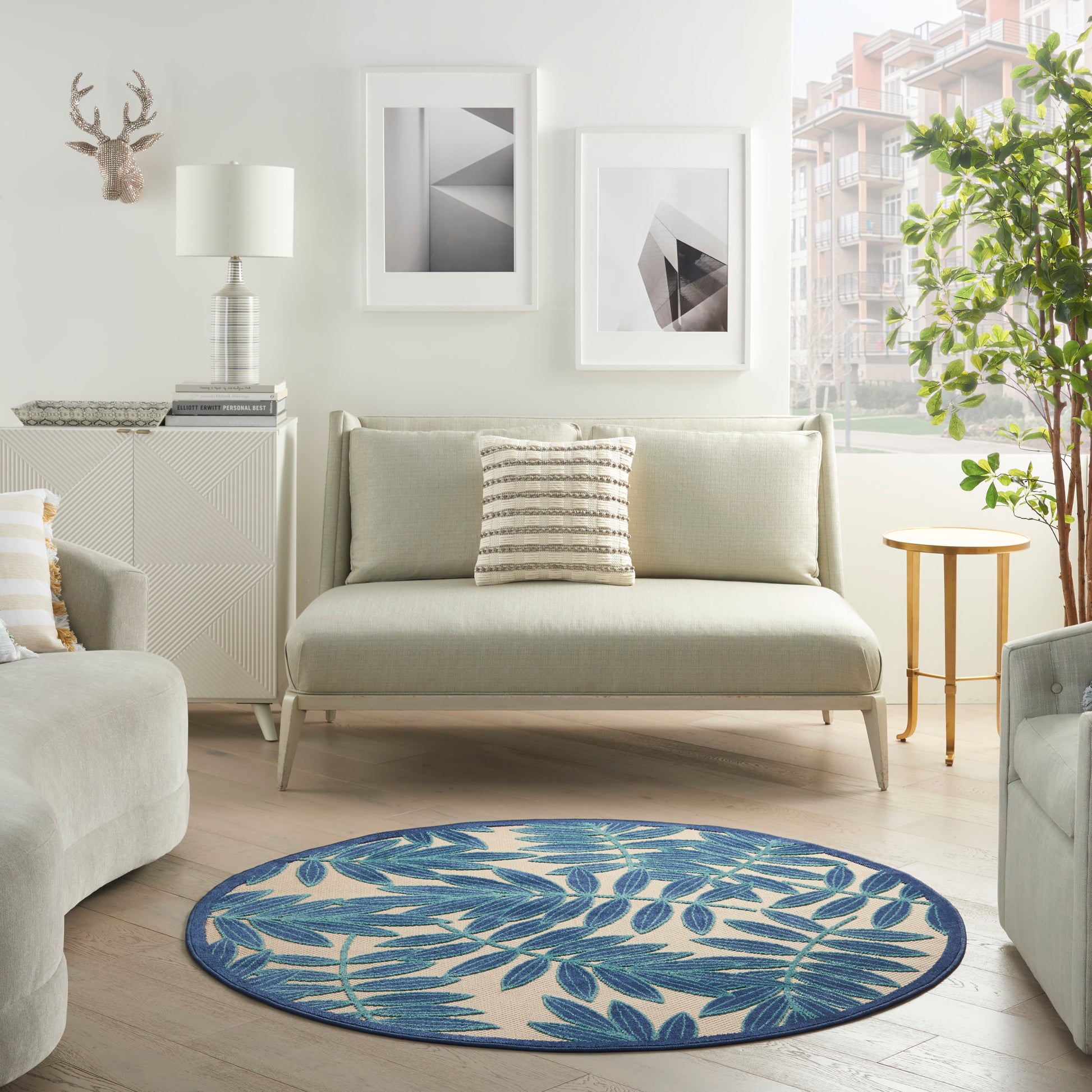 Round blue botanical rug with leaf motif and woven texture in a light, neutral living room.