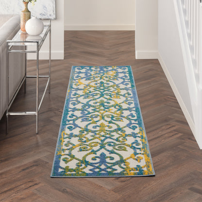 Long rectangular rug runner with blue, teal, and yellow scrollwork in a modern hallway beside a glass-console table.
