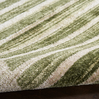 Close-up of a green & beige striped rug with a plush pile and edge on dark wood floor.