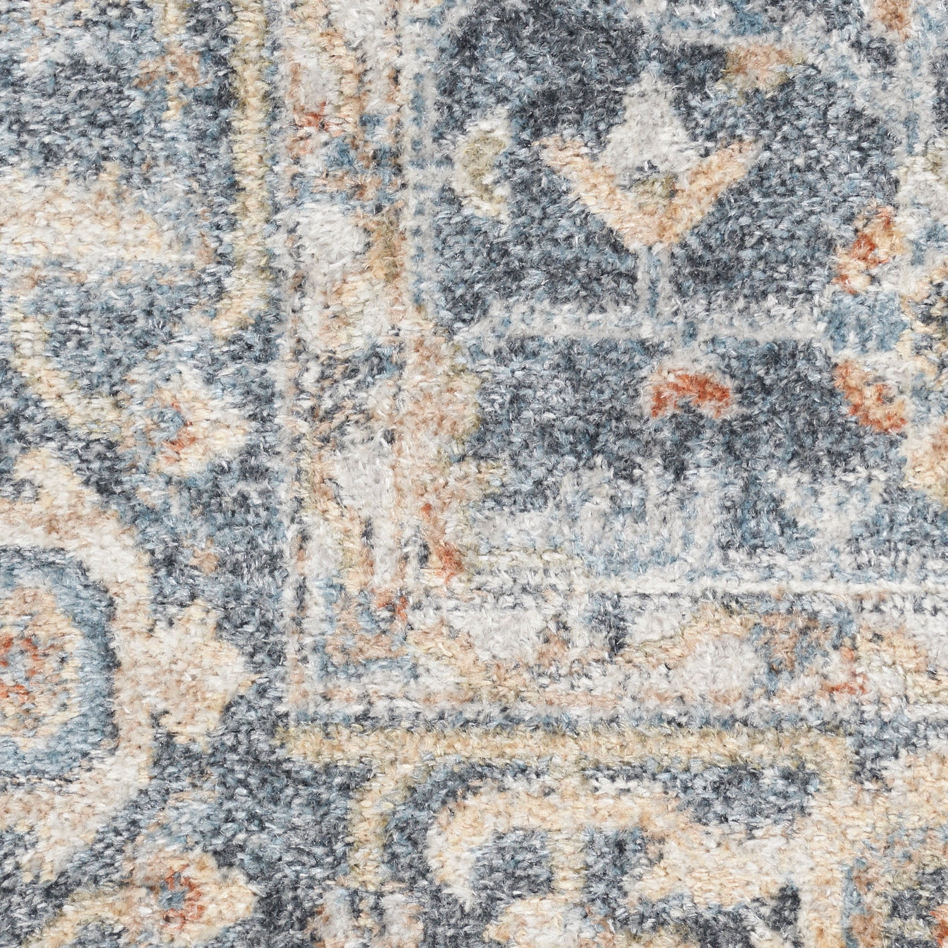 Close-up of a blue-gray and beige patterned rug with ivory scrolls and floral motifs, plush pile.