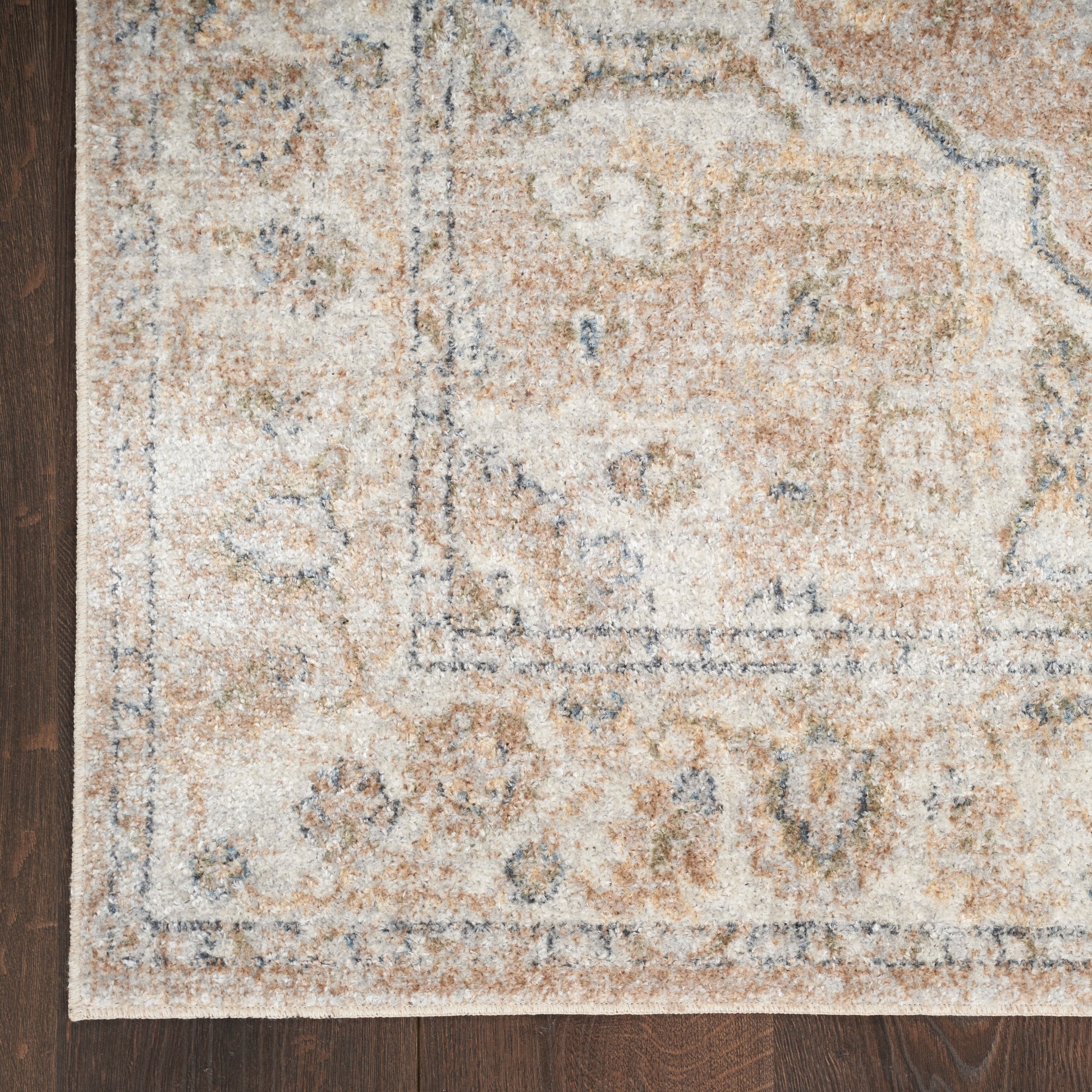 Rectangular beige distressed oriental rug with blue-gray border on dark wood floor.