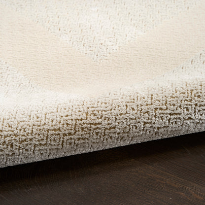 Cream beige shag rug with a textured Greek key border, thick plush pile on dark wood floor.