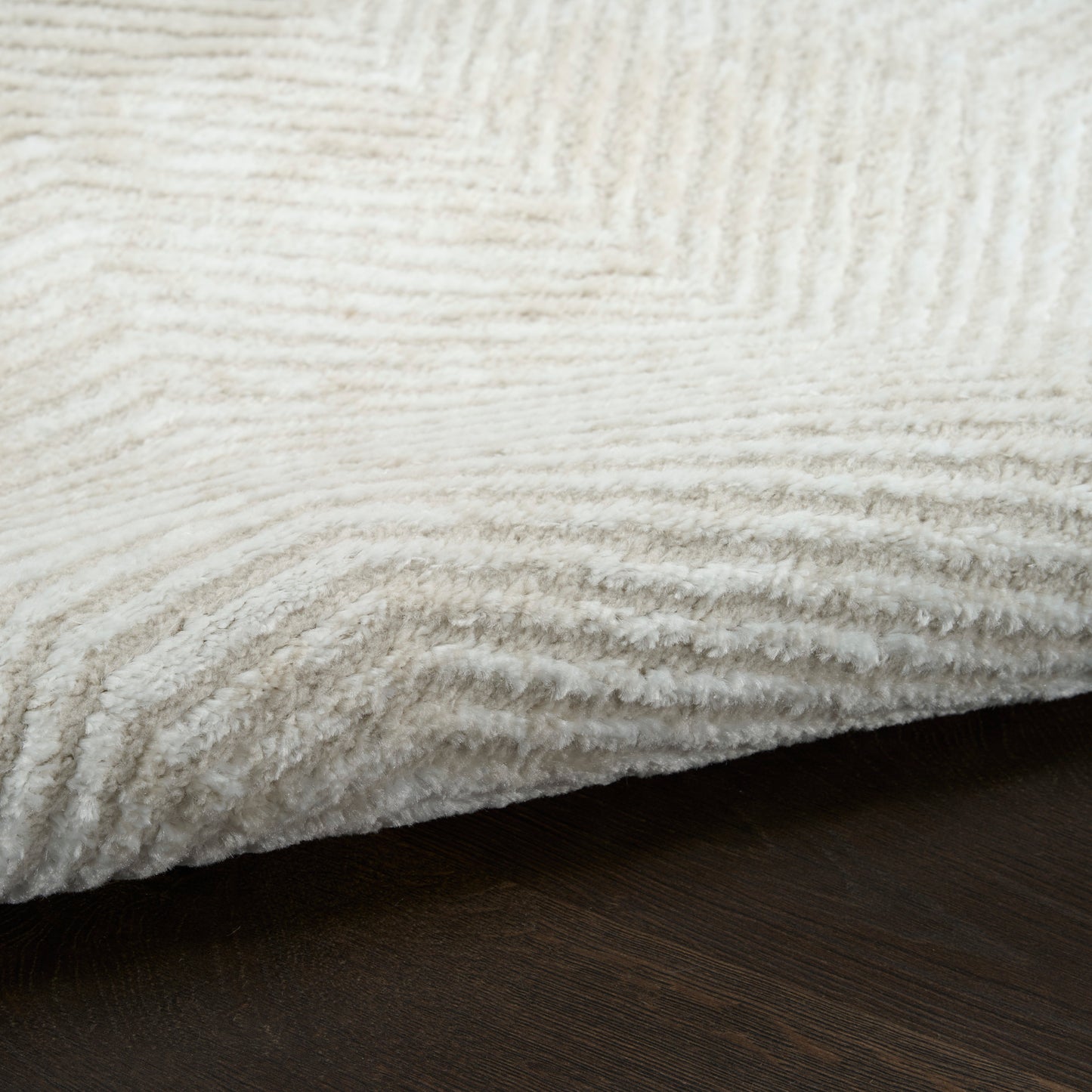 White plush rug with thick ribbed pile on dark wood floor.