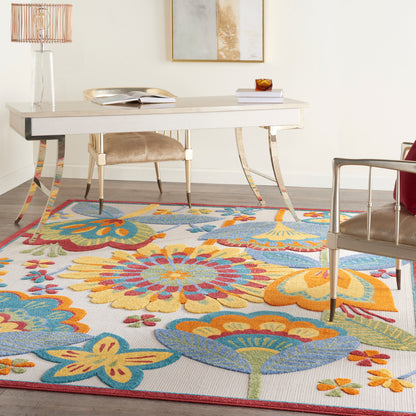 Bold multicolor floral rug (9' x 12') in a contemporary setting, seen with a white desk, beige upholstered chair, and glass lamp.