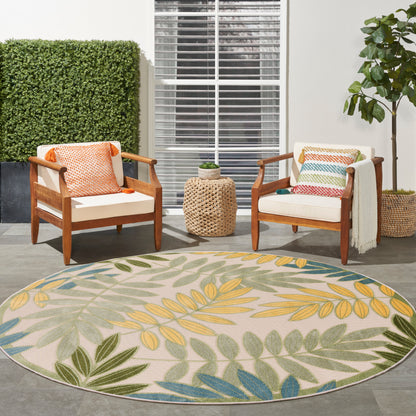 Outdoor patio: round leaf-pattern rug in yellow, green & blue; two wooden armchairs with white cushions and colorful pillows.