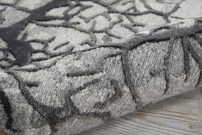 Gray abstract patterned rug with charcoal lines, plush pile, rolled edge on light wood floor.