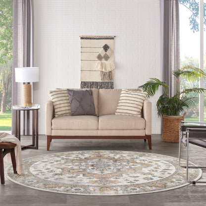 Beige mid-century sofa with two striped cushions and a gray quilted cushion, circular patterned rug, woven wall hanging, plant, and glass side table.