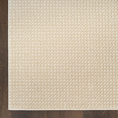 Beige woven rug with textured loop pile, rectangular shape, cream tones, placed on dark wood floor