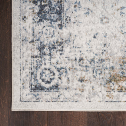 Muted blue & ivory oriental rug with a faded geometric floral pattern on dark wooden floor.
