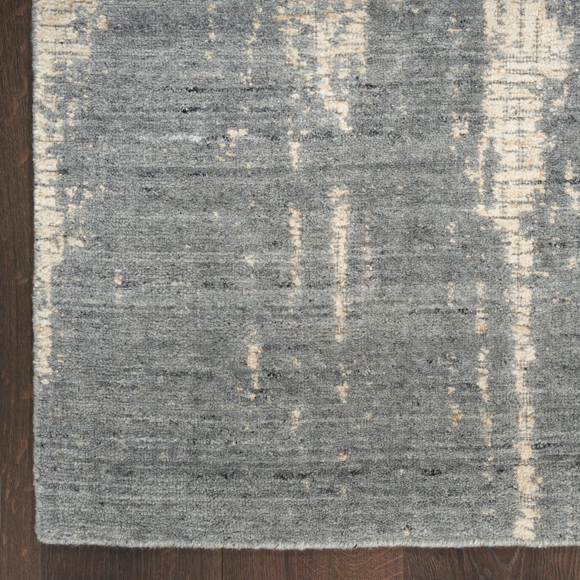 Rectangular grey-blue area rug with cream vertical streaks, low-pile woven texture on dark wooden floor.