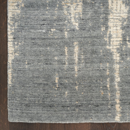 Rectangular grey-blue area rug with cream vertical streaks, low-pile woven texture on dark wooden floor.