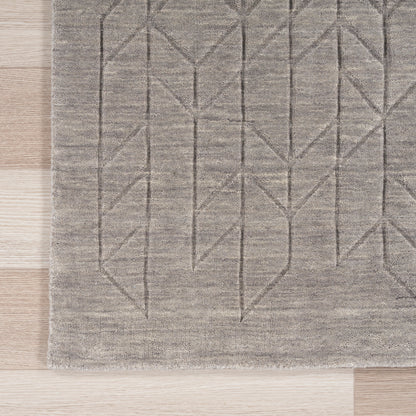 Gray rectangular area rug with geometric chevron and diamond motif on light wood floor.