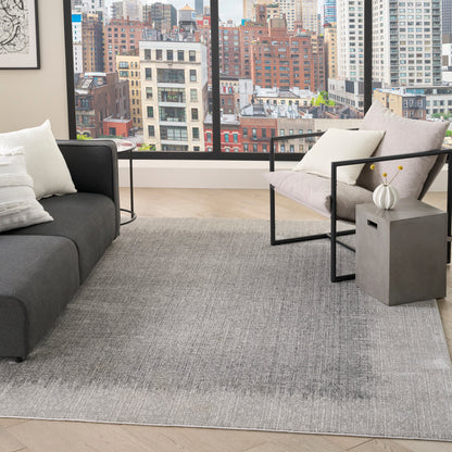 Modern living room with gray sofa, metal-framed chair, large city skyline view, and light gray rug.