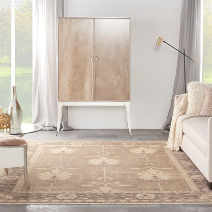 Beige wood armoire on slim legs in a bright living room with a floral beige rug, cream sofa, and gold floor lamp.