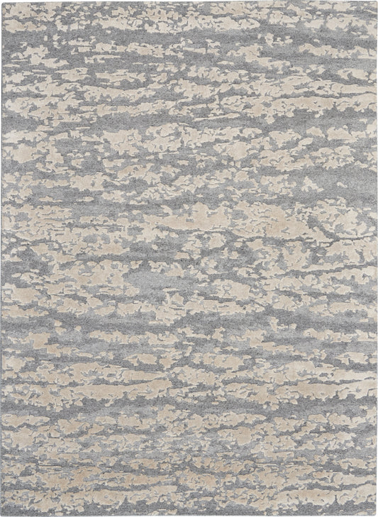 Rectangular gray-blue rug with cream cloudlike abstract pattern; soft woven texture, modern coastal style.