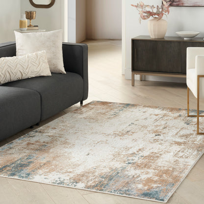 Abstract distressed area rug in beige, blue, and gray tones under a dark gray sofa in a modern living room.
