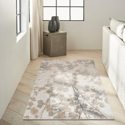 Rectangular neutral area rug with soft beige-taupe-gray botanical pattern on light wood floor in a minimalist living room.