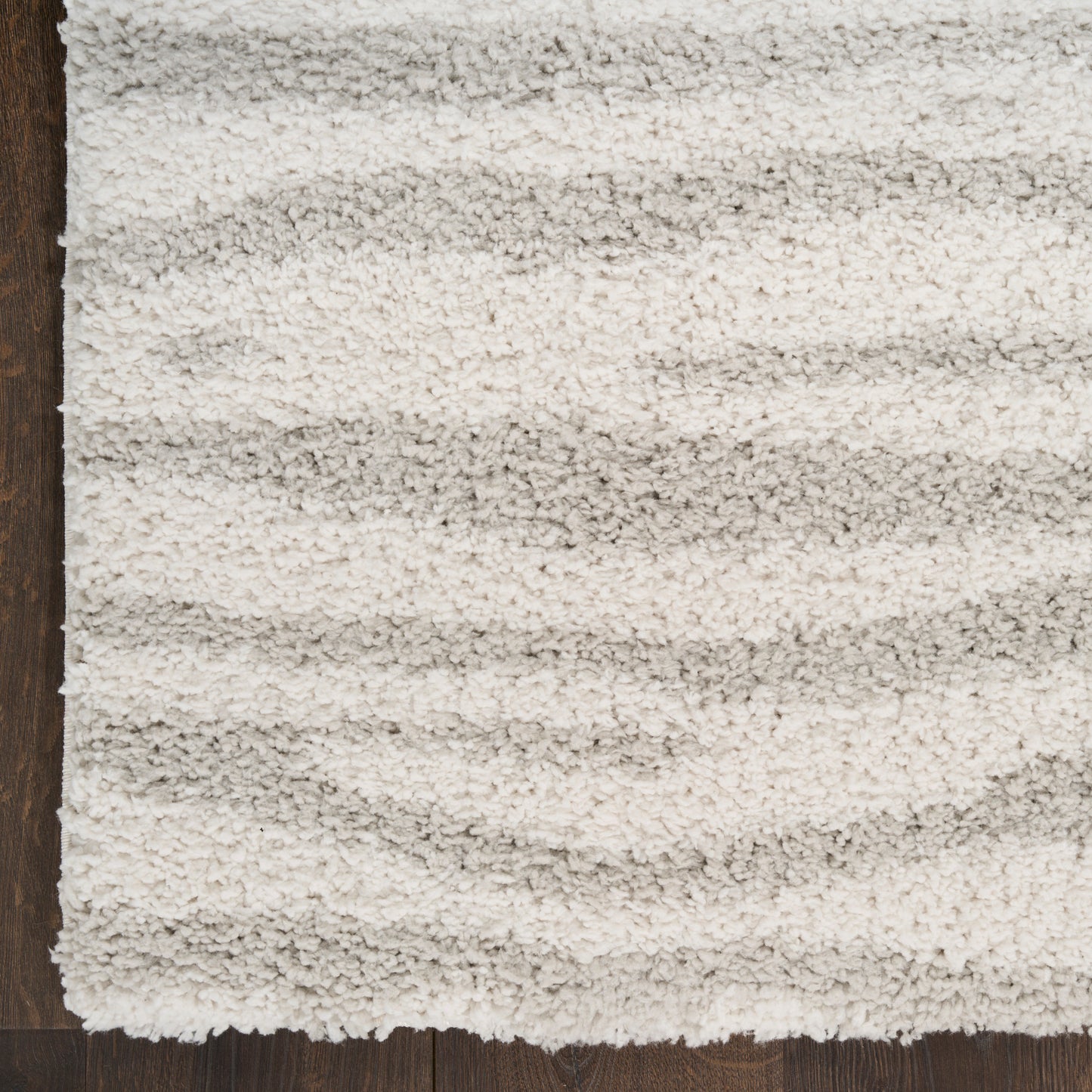 Cream shag rug with plush high-pile texture and subtle light gray stripes on dark wood floor.