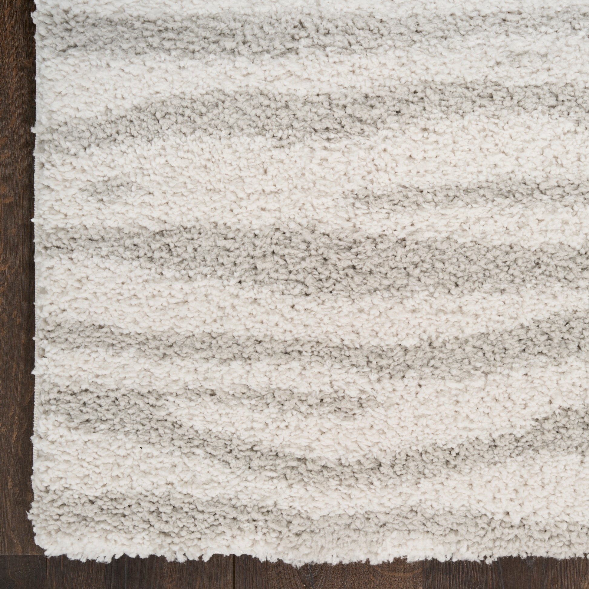 Cream shag rug with plush high-pile texture and subtle light gray stripes on dark wood floor.