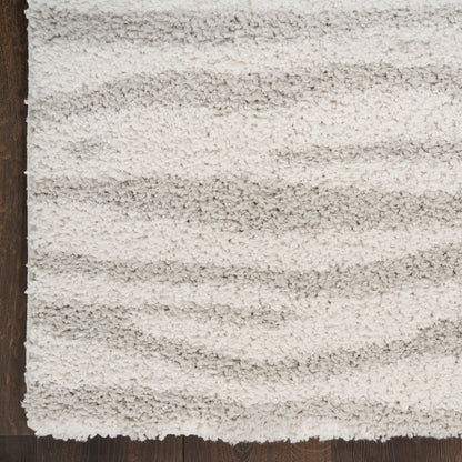 Cream shag rug with plush high-pile texture and subtle light gray stripes on dark wood floor.