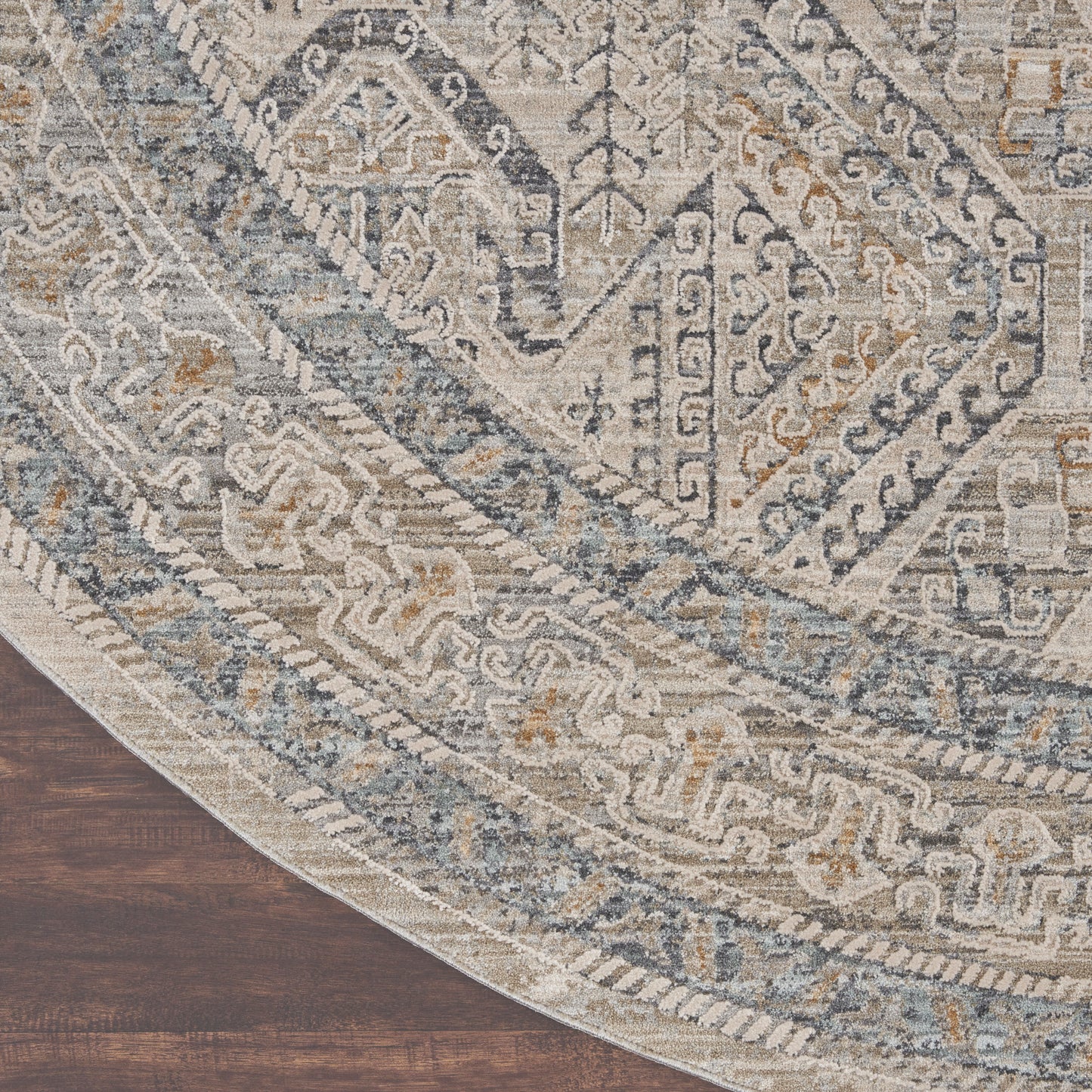 Round oriental-inspired rug in blue, gray and ivory with intricate geometric borders on dark wood floor.