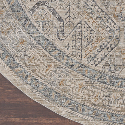 Round oriental-inspired rug in blue, gray and ivory with intricate geometric borders on dark wood floor.