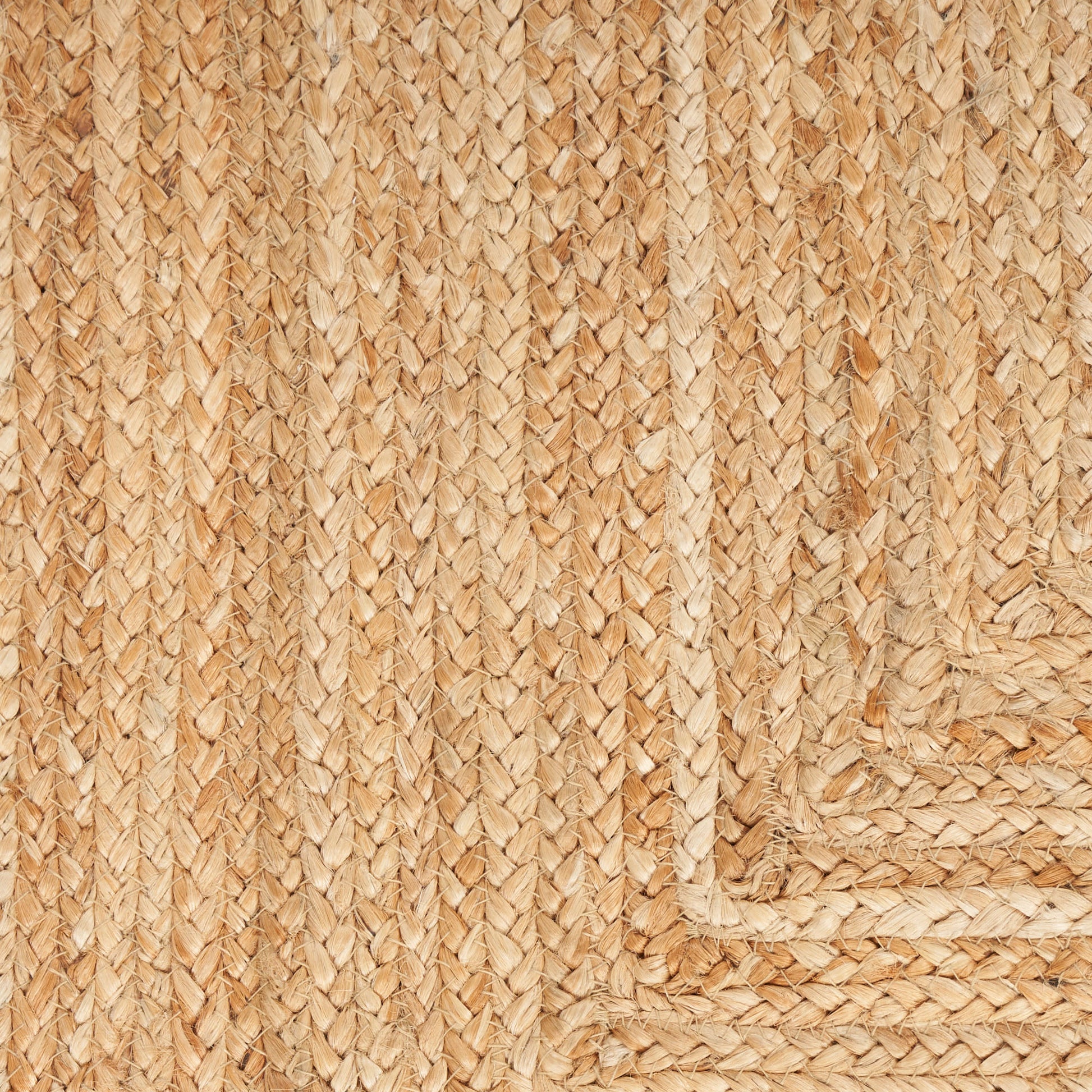 Natural tan braided jute rug, close-up of woven texture and corner border.