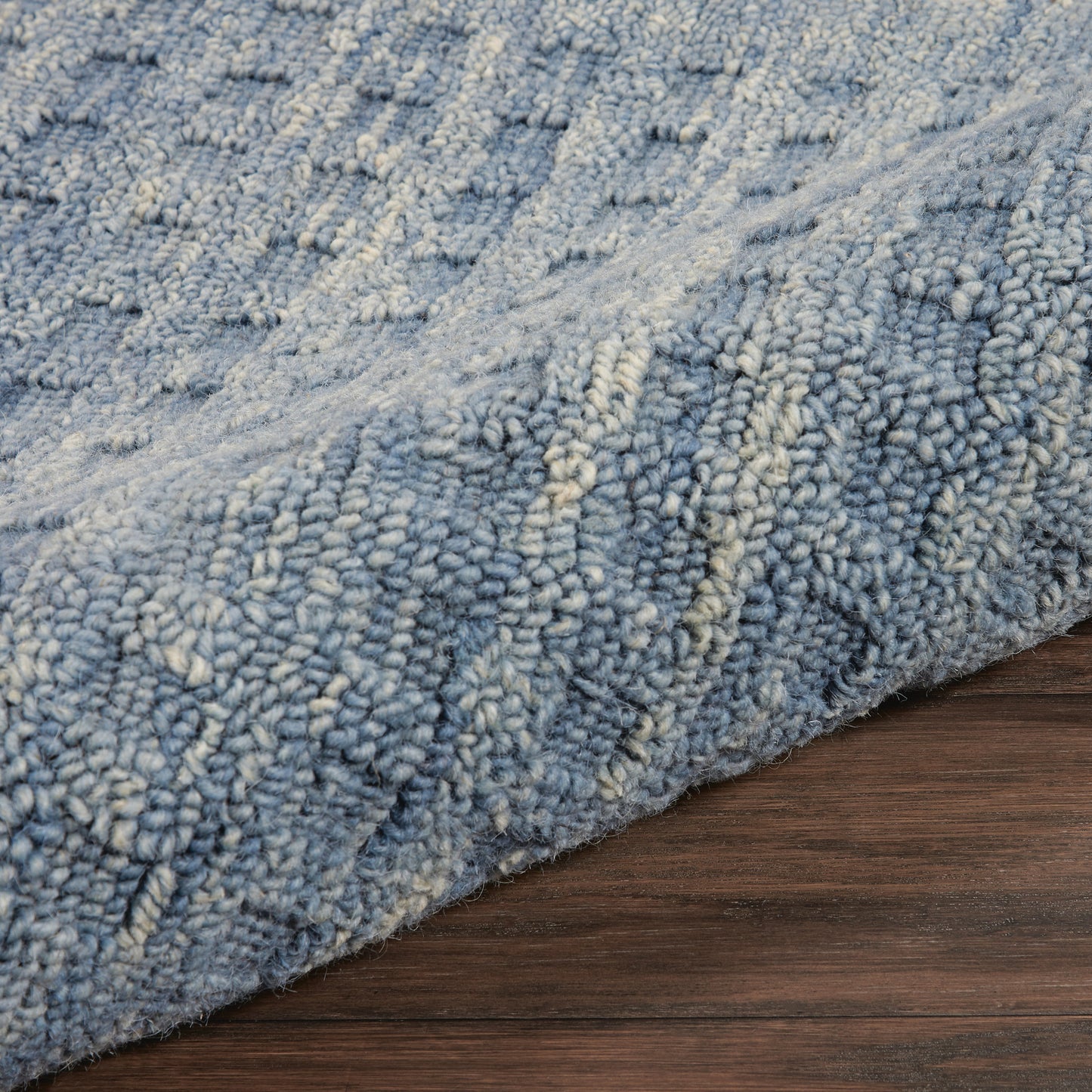 Blue shag rug with cream highlights, plush pile, modern textured pattern on dark wood floor.