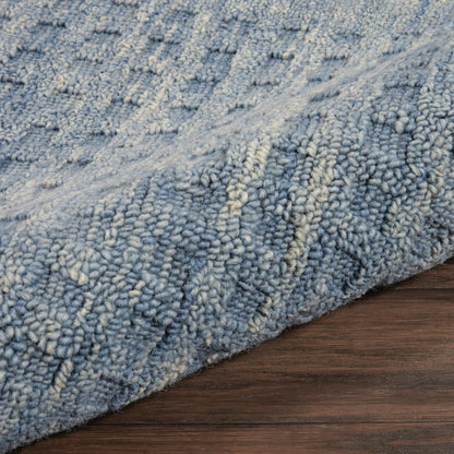 Blue shag rug with cream highlights, plush pile, modern textured pattern on dark wood floor.