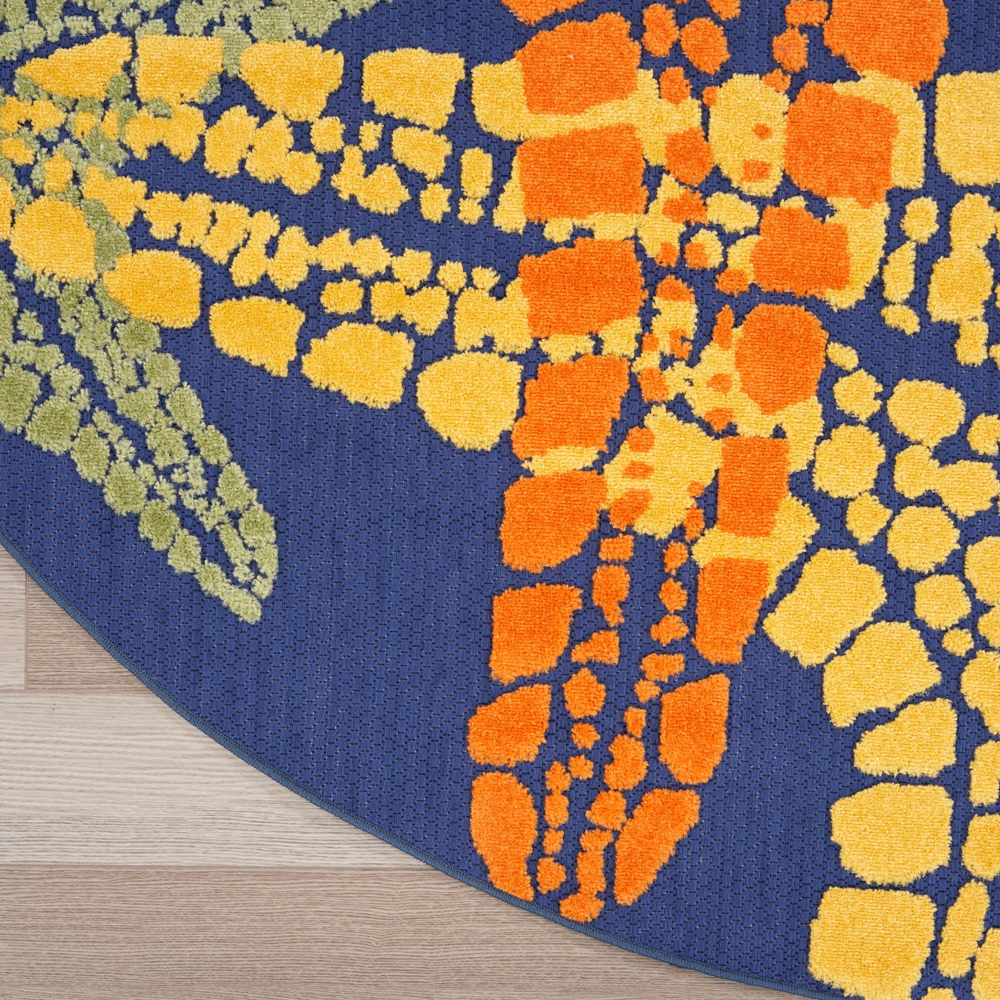 Round blue rug with bright orange and yellow mosaic blocks in an abstract pattern.