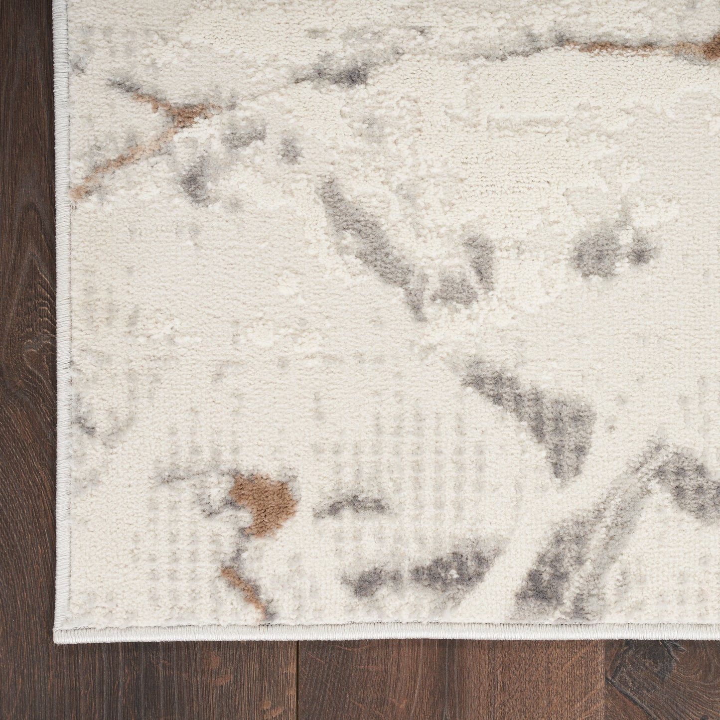 Cream & gray abstract-area rug with taupe & rust accents on dark wood floor, bound edge.