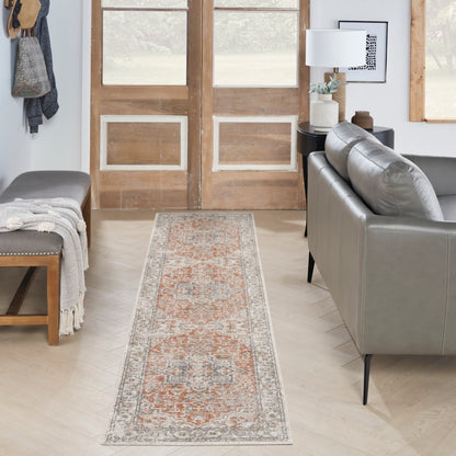 Rustic living room entry with a vintage 8' runner rug in orange and grey, a grey leather sofa, wooden double doors, and a bench with a throw.