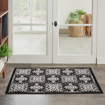 Black and white damask-style entryway rug in front of white-framed glass doors.