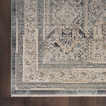 Blue and ivory oriental rug with ornate geometric motifs and fringed border on dark wood floor.