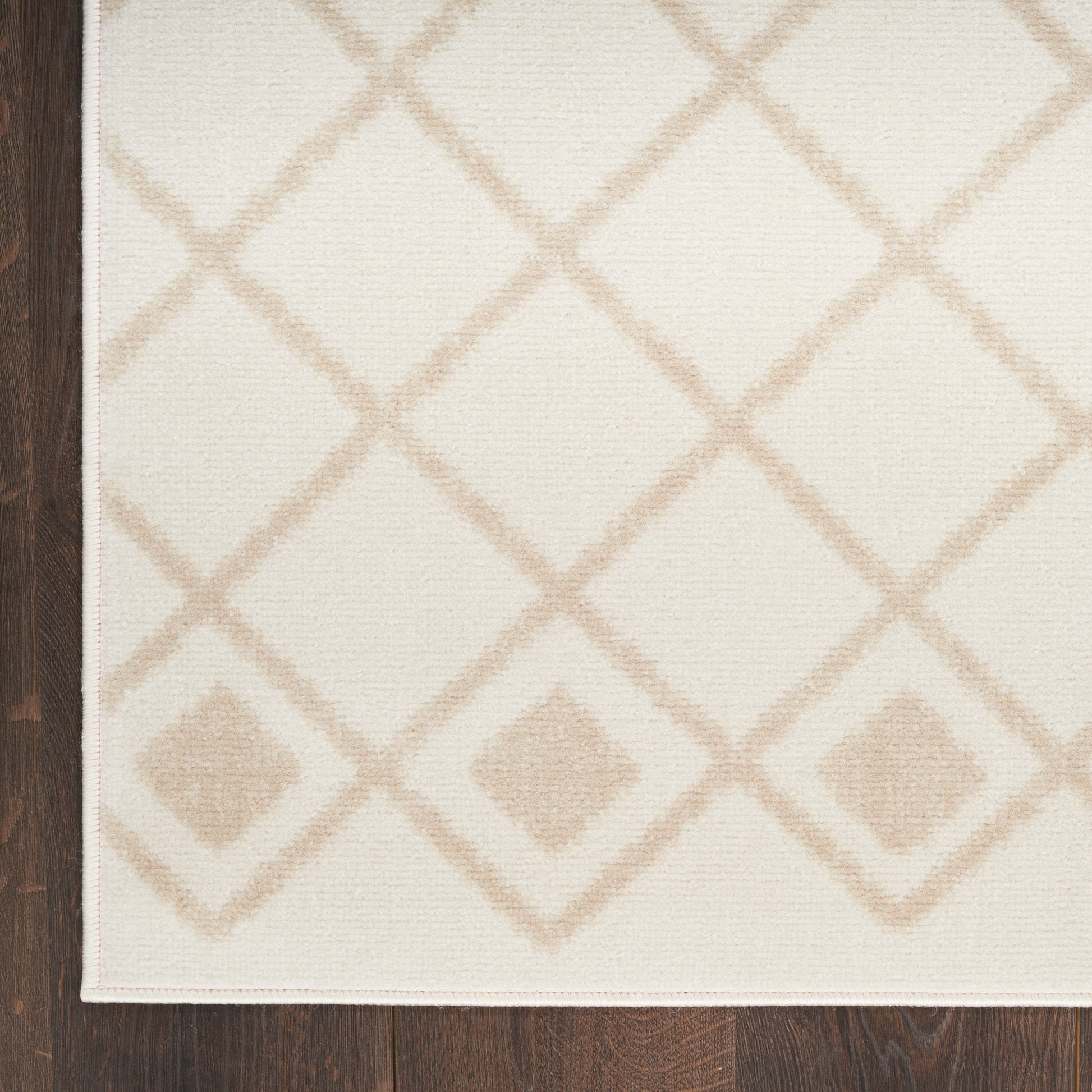 Cream area rug with light beige diamond lattice pattern on wood floor; rectangular woven textile for cozy living room floors.