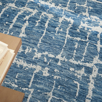 Blue textured area rug with white abstract geometric lattice pattern; wooden coffee table with books nearby.