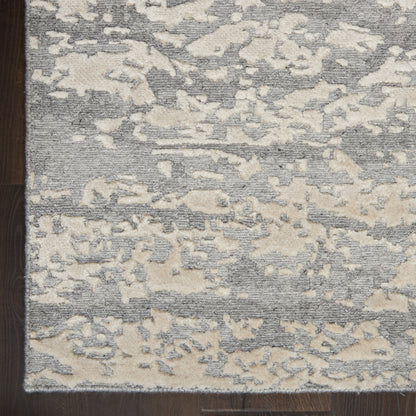 Abstract gray and beige area rug with distressed pattern on dark wood floor; low-pile, modern rectangular rug.